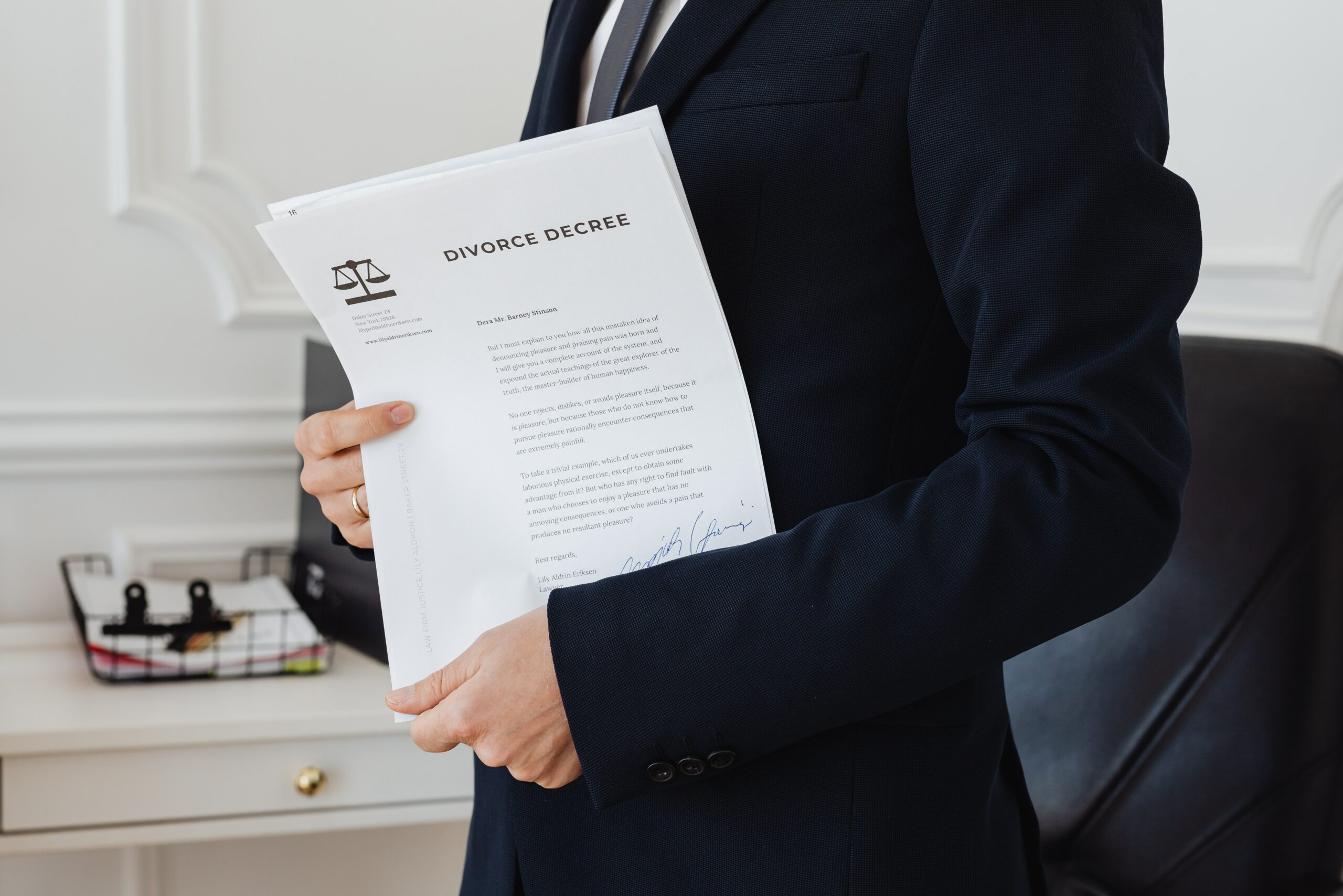 Lawyer’s torso and arms holding papers titled “divorce decree” in an office